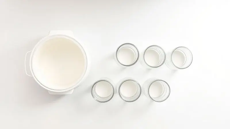 An overhead flat lay shot of a pristine white kitchen counter displaying several different yogurt maker inserts: a single lar