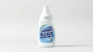 Fotografia profissional de uma embalagem de alvejante moderna ao lado de uma toalha branca, representando os melhores alvejantes do mercado.