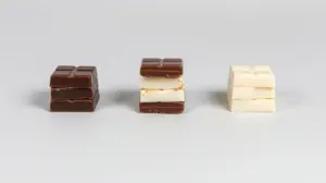 Fotografia profissional de uma pilha de chocolates amargo, ao leite e branco, representando as melhores marcas de chocolate do mercado.