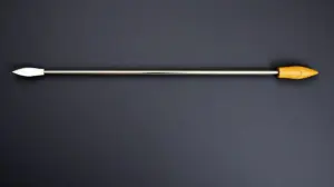 Um espeto para churrasco de aço inox com cabo de madeira, visto em detalhe sobre um fundo escuro, representando os melhores espetos para comprar em 2024.