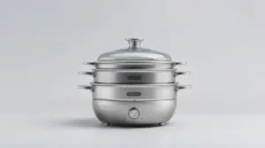 Uma moderna panela a vapor de aço inoxidável, sem marca, em um fundo de estúdio claro, mostrando seus detalhes, múltiplos andares e a tampa de vidro.