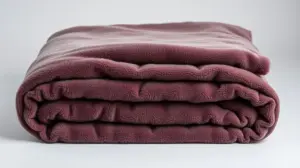 Pilha de cobertores de microfibra luxuosos em cores neutras, dobrados perfeitamente, mostrando a textura macia e aconchegante do tecido em close.