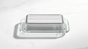 Uma elegante manteigueira de vidro sobre uma superfície de mármore branco, representando as melhores manteigueiras para comprar.