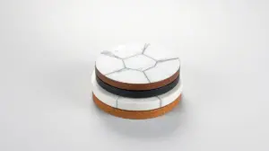Pilha de porta-copos elegantes e sem marca, feitos de materiais diversos como mármore e madeira, em um fundo de estúdio com iluminação profissional.